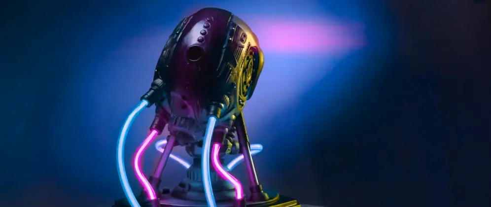 The image shows the back view of a sculpture titled “VOLTA” from the PROJECT AD-01 series by Freaky Deek. The sculpture depicts a futuristic android with a sleek, metallic body. The back of the android is detailed with smooth surfaces and intricate mechanical elements. Purple LED lights illuminate various sections, particularly along the spine, highlighting the contours and giving the sculpture a glowing, high-tech appearance. The dark background contrasts with the bright lights, making the illuminated details stand out vividly.